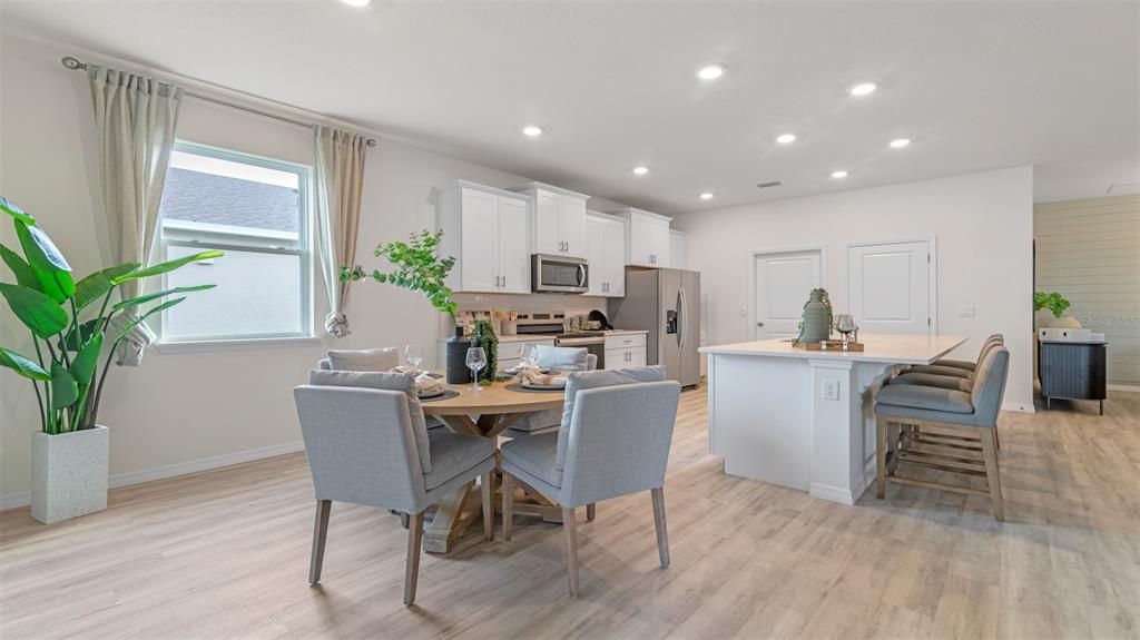 A kitchen and dining area with white cabinets, a central island, and light wood flooring — 3042 KINGSMAN TRAIL, ORMOND BEACH, FL