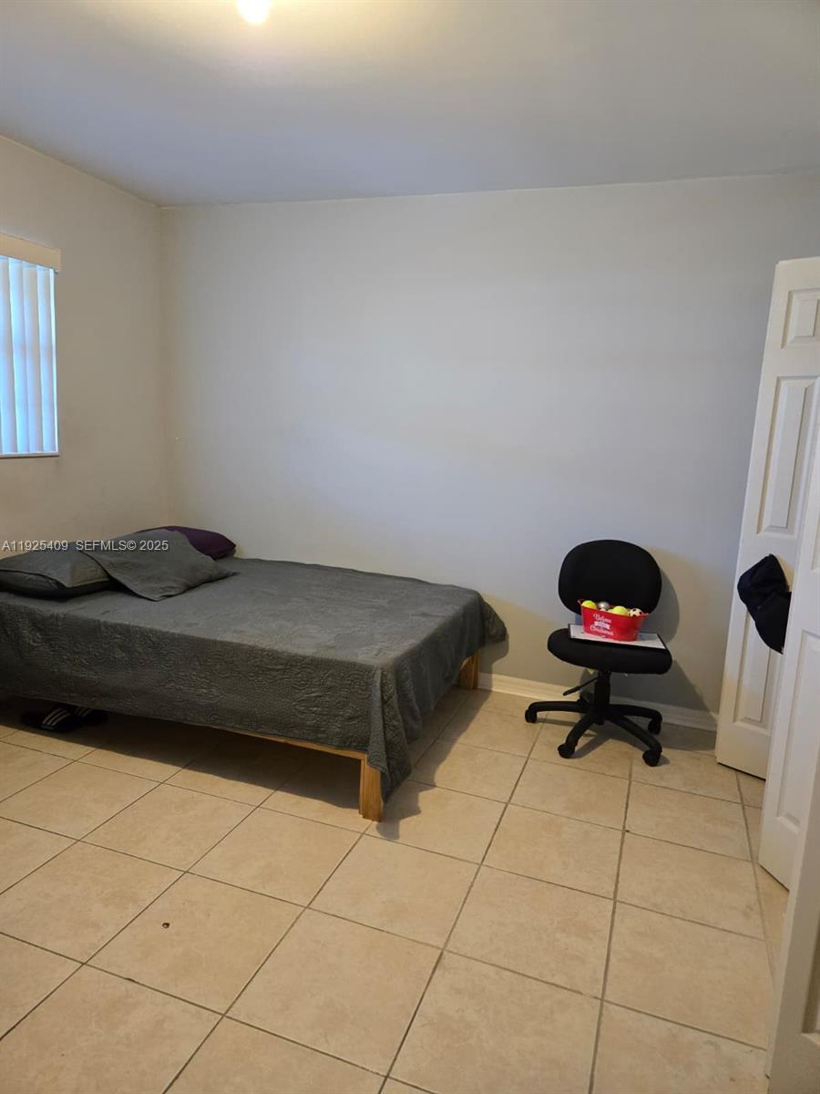 A bedroom features a bed with a gray cover, a desk chair, and tile flooring — 7837 Golf Cir Dr # 310, Margate FL 33063, MARGATE, FL