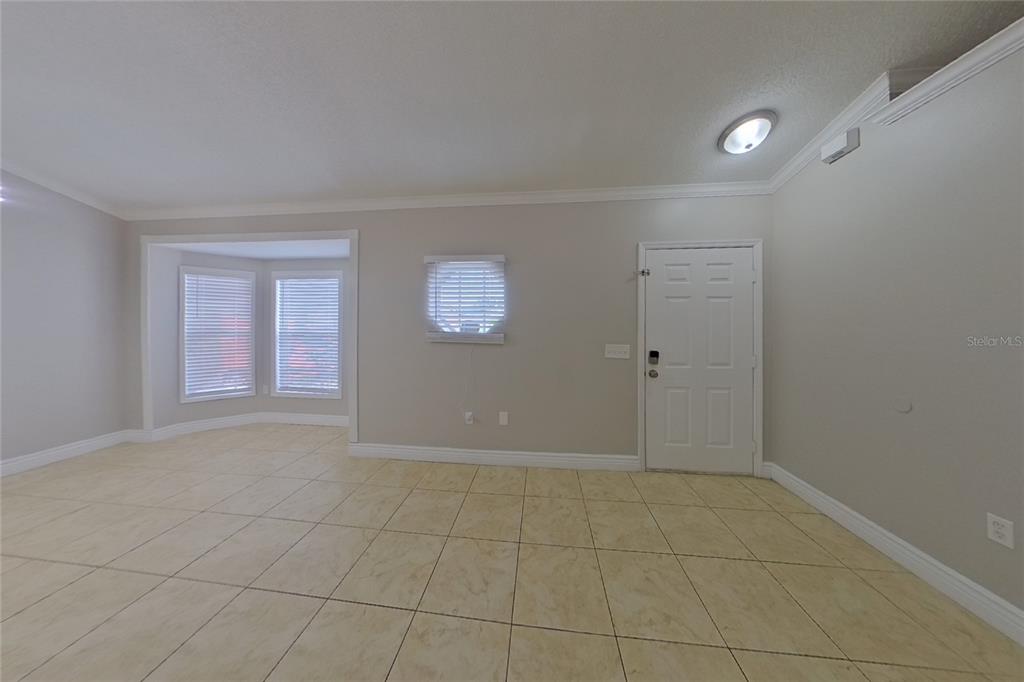 A room with beige tile flooring, a bay window, a small square window, and a door — 312 COLONY COURT, KISSIMMEE, FL