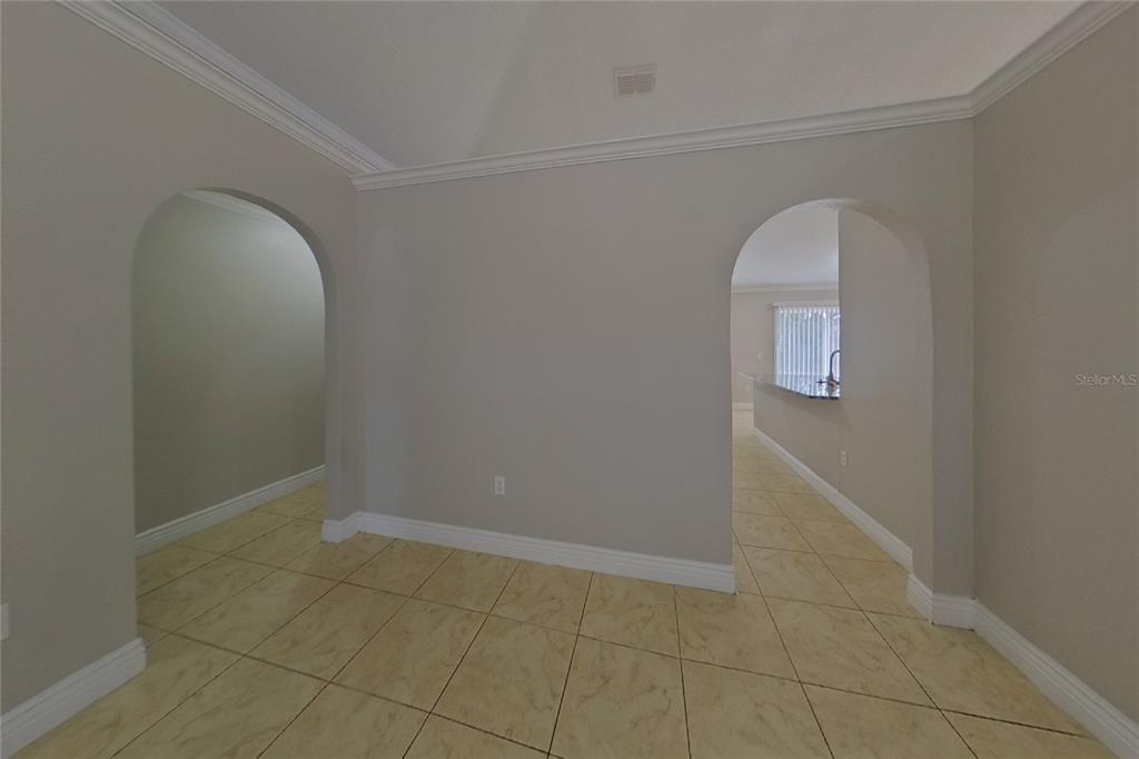 A room with beige tile flooring and two arched doorways leading to other areas — 312 COLONY COURT, KISSIMMEE, FL