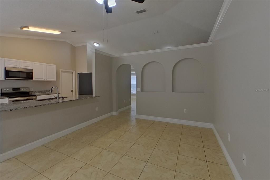 This room features beige tile flooring, a kitchen breakfast bar, and two arched wall niches — 312 COLONY COURT, KISSIMMEE, FL