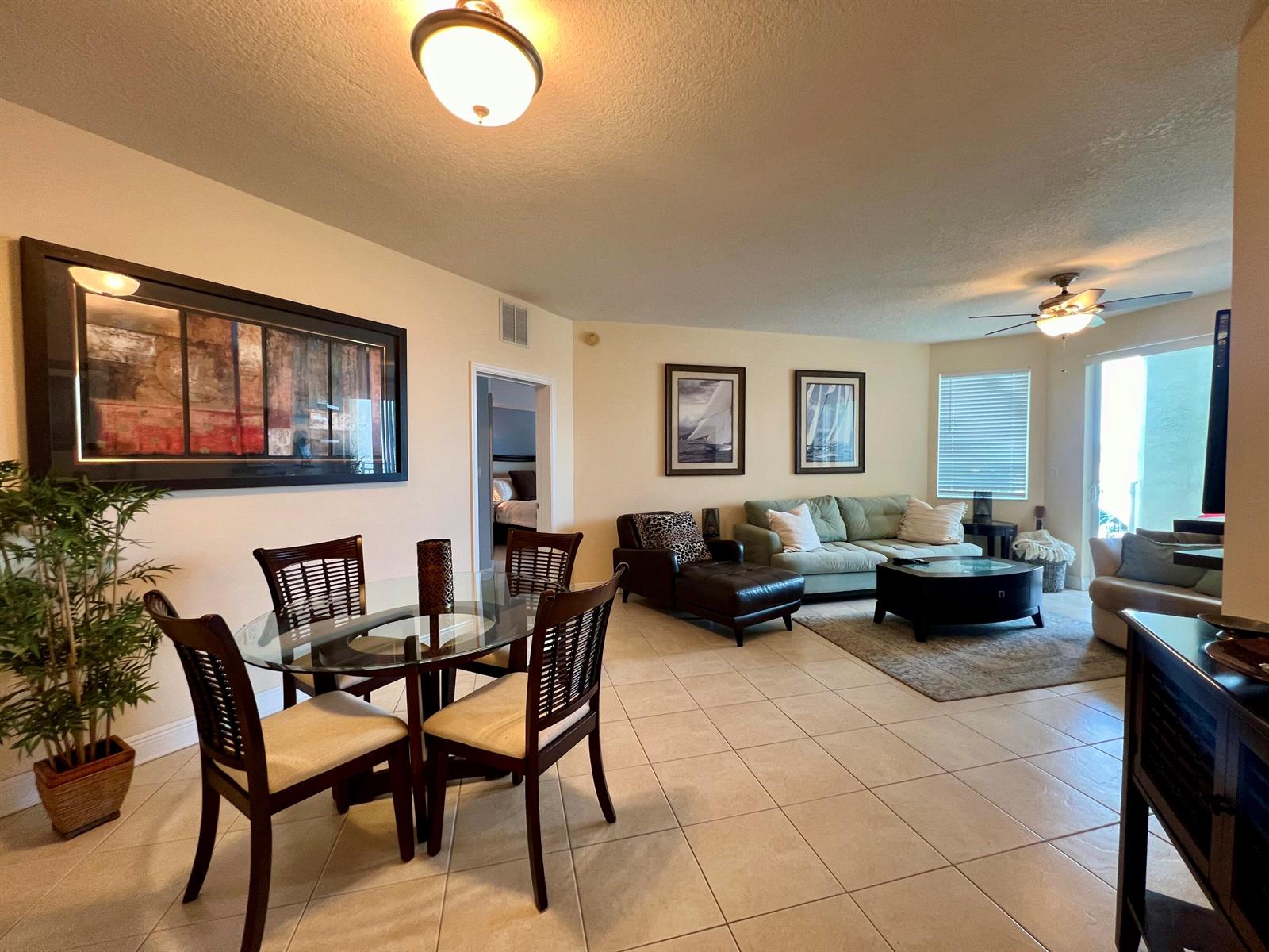 An open-concept living and dining area features tile flooring, a glass table, and neutral walls — 975 NW Flagler Avenue, Stuart FL 34994, STUART, FL