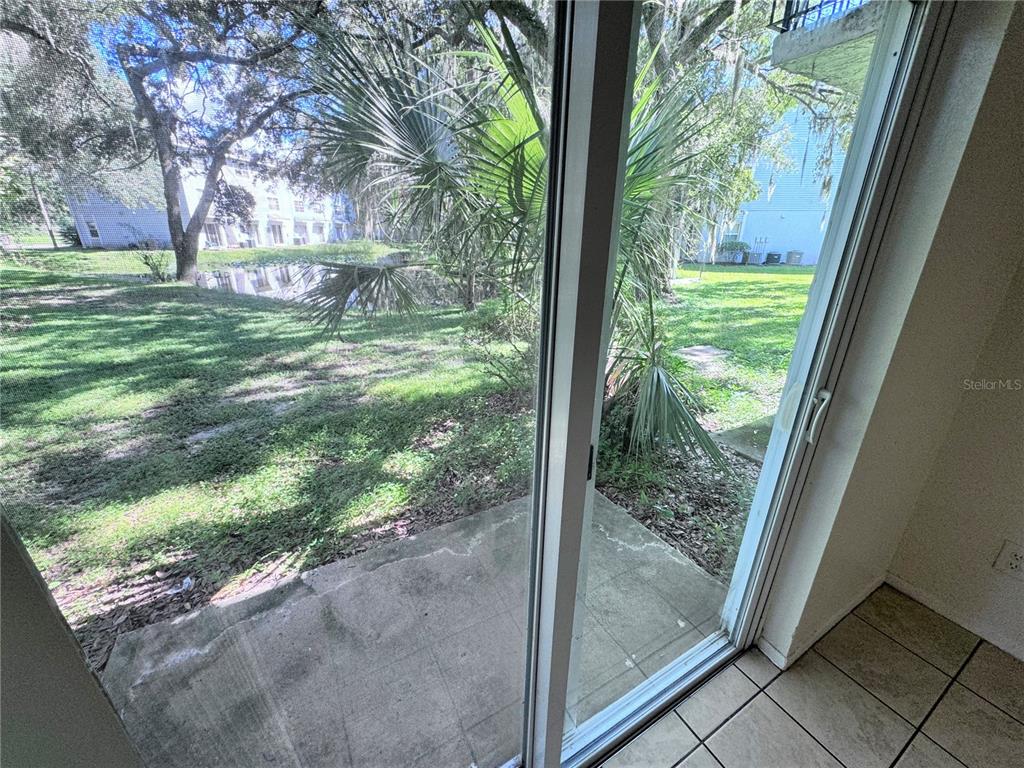 A sliding glass door opens from a tiled room onto a concrete patio and yard — 7177 E BANK DRIVE UNIT 102, TAMPA, FL