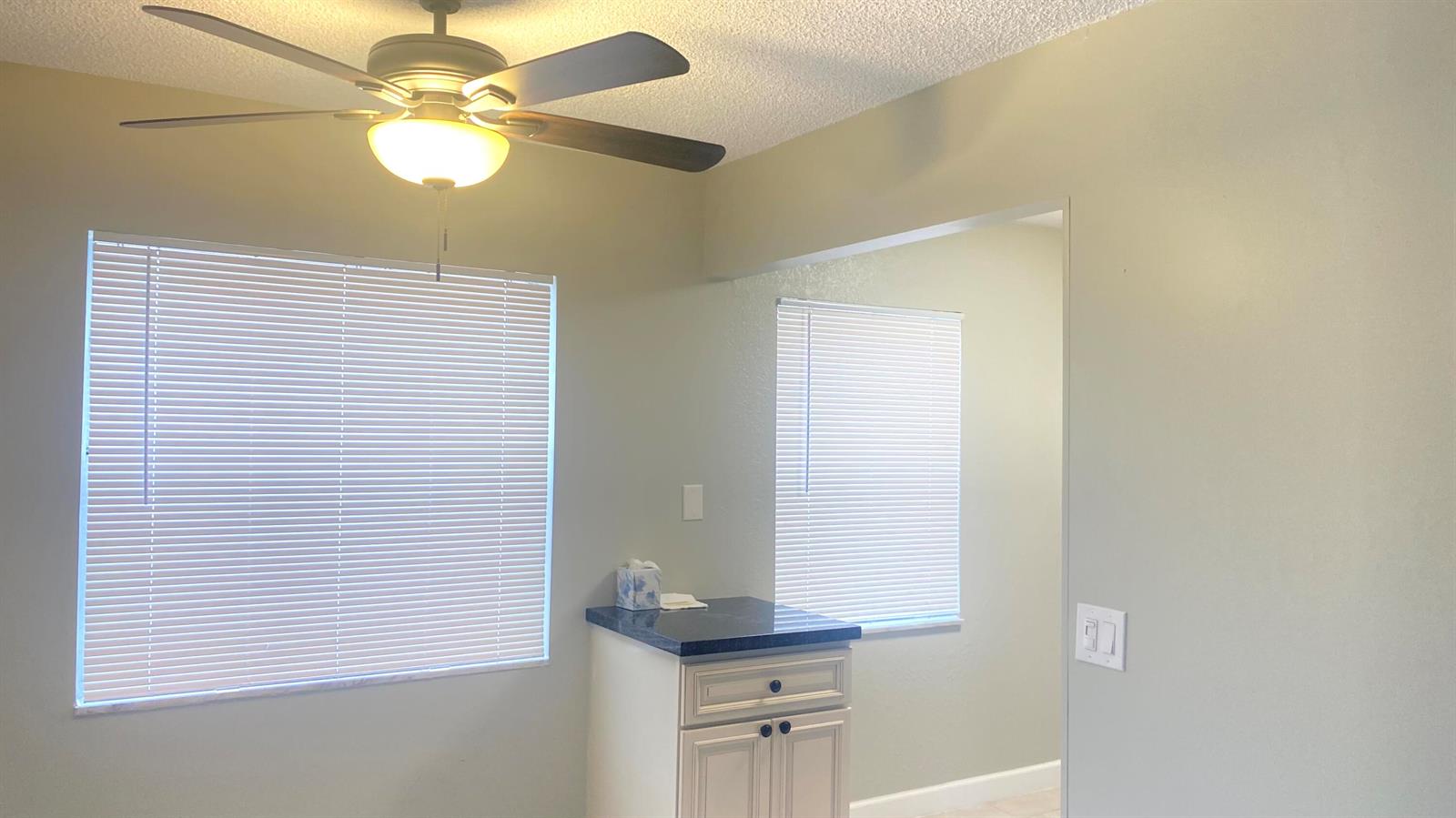 A room features a ceiling fan, two windows with blinds, and a small cabinet — 177 Flanders D # 177, Delray Beach FL 33484, DELRAY BEACH, FL