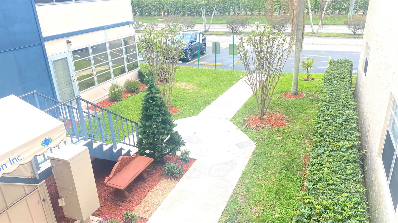 An elevated view shows a building exterior with a walkway, landscaping, and a small bench — 177 Flanders D # 177, Delray Beach FL 33484, DELRAY BEACH, FL