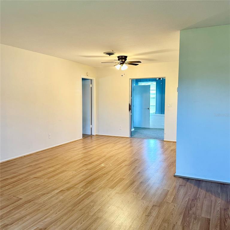 A living room with light wood-look flooring, a ceiling fan, and two doorways — 340 PEARY ROAD, VENICE, FL