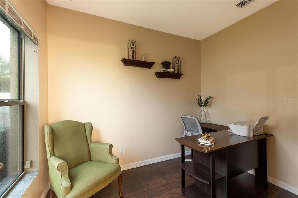 A home office features a green armchair, a dark wood desk, and two wall-mounted shelves — 2722 BIG TIMBER DRIVE, KISSIMMEE, FL