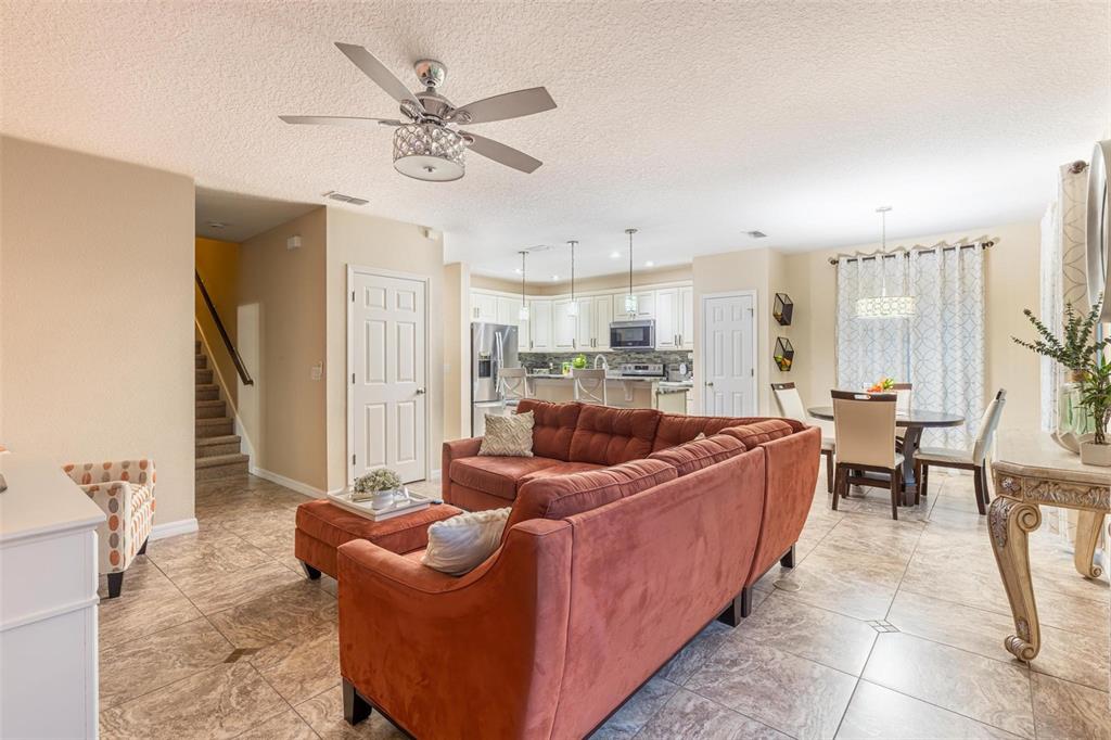 An open-concept living room and kitchen feature tile flooring, a sectional sofa, and stairs — 2722 BIG TIMBER DRIVE, KISSIMMEE, FL