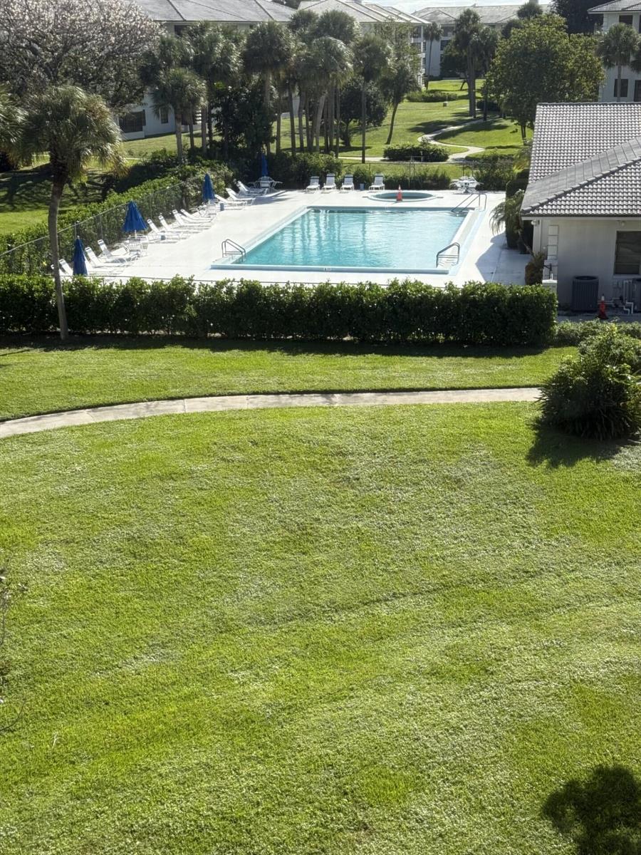 An elevated view shows a rectangular swimming pool with lounge chairs and a grassy lawn — 3710 Whitehall Drive # 401, West Palm Beach FL 33401, WEST PALM BEACH, FL