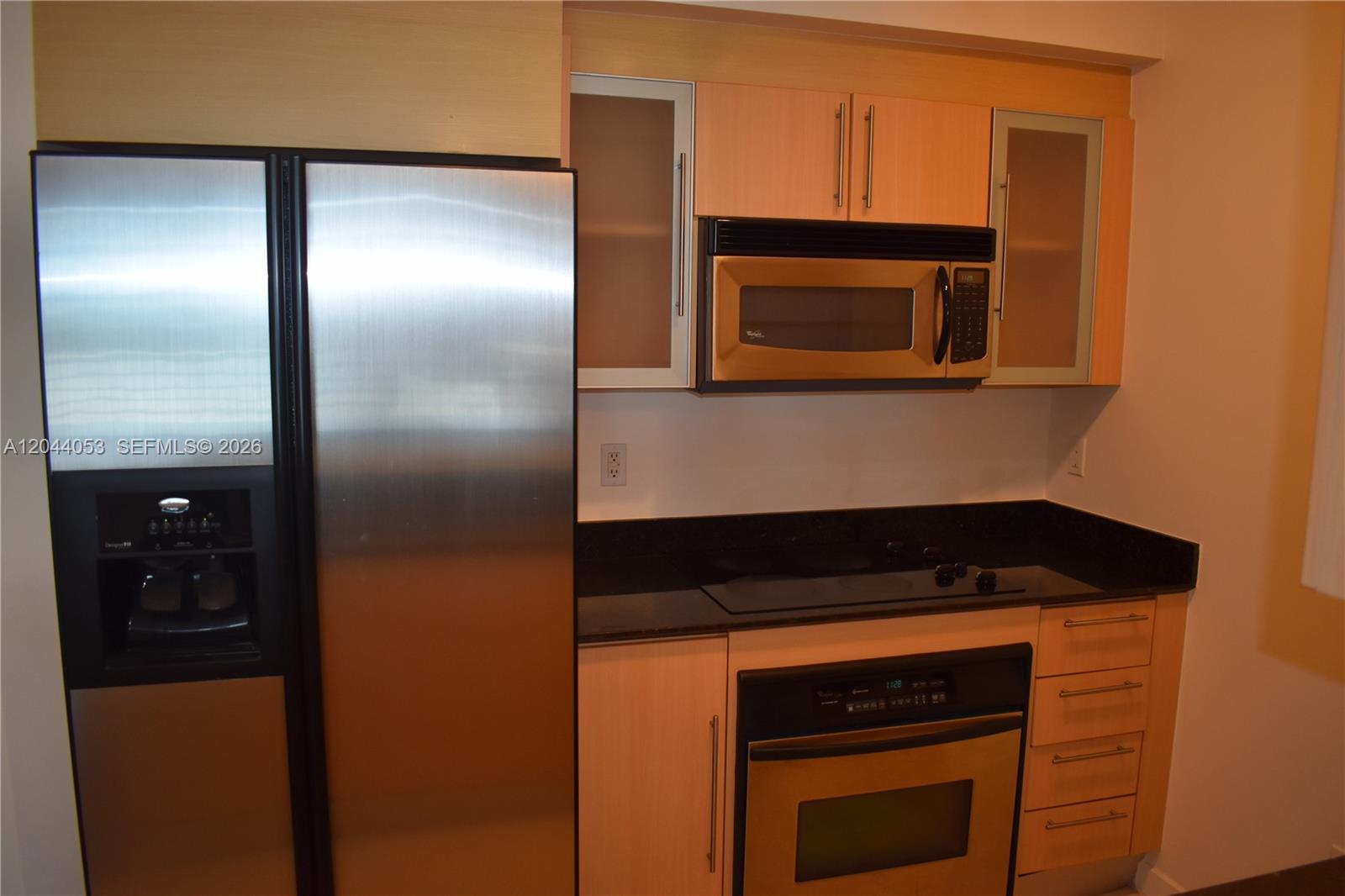 A kitchen features stainless steel appliances, light wood cabinets, and black granite countertops — 325 S Biscayne Blvd # 3616, Miami FL 33131, MIAMI, FL