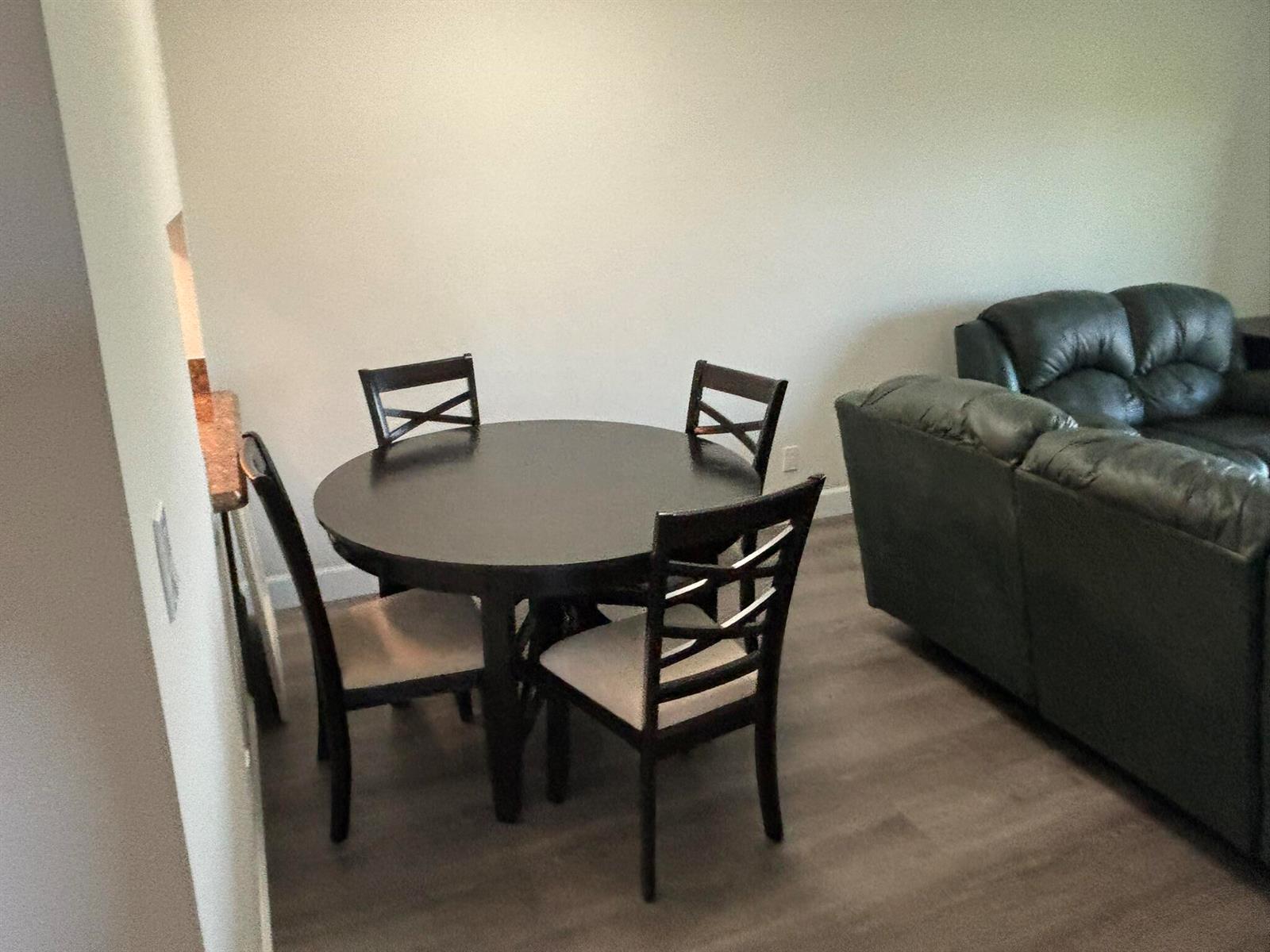 A dining area with a round dark wood table and four chairs next to a sofa — 2668 Garden Drive N # 312, FL 33461, FL