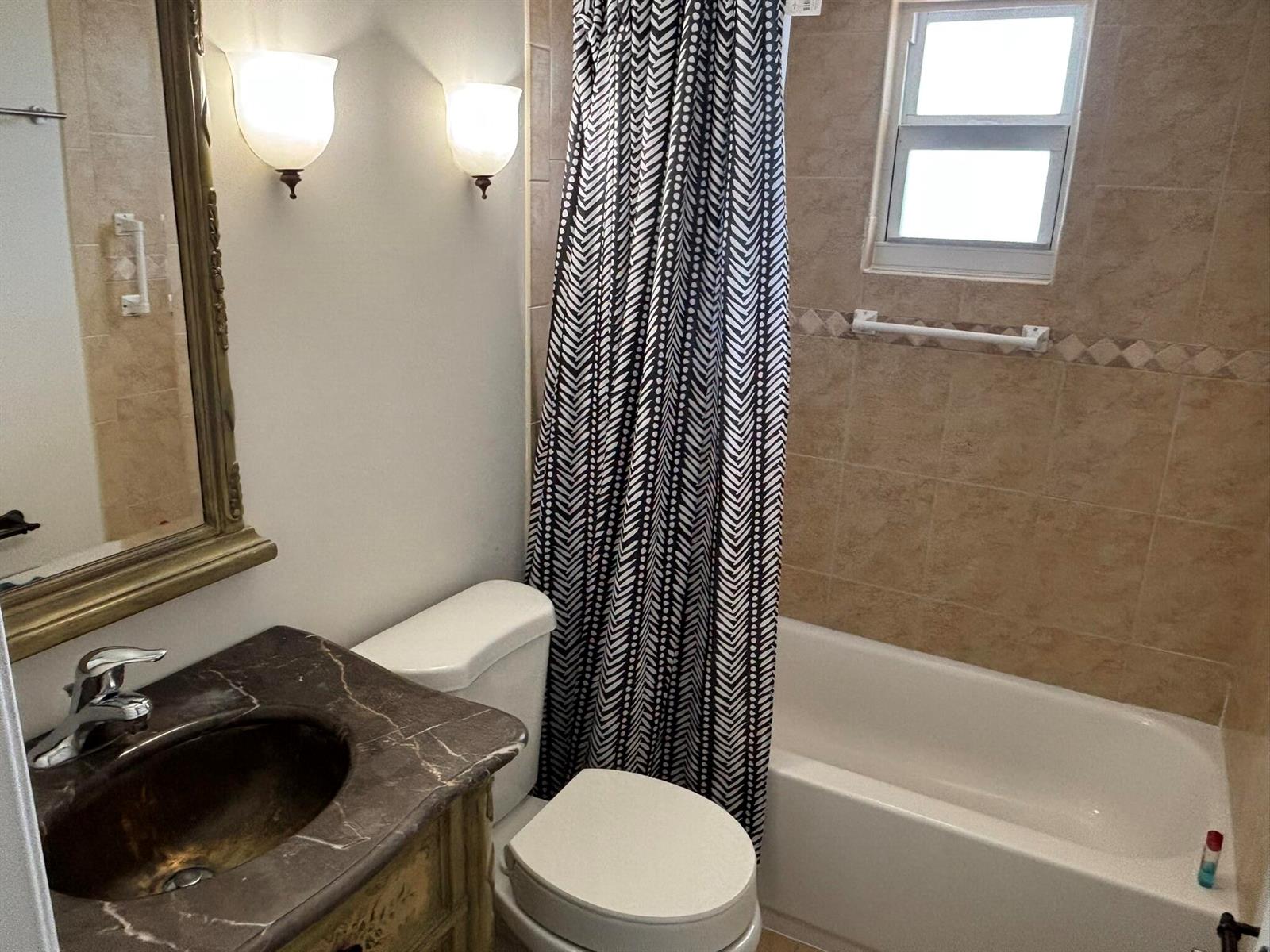 A bathroom features a marble vanity, a toilet, and a shower-tub combo with tiled walls — 2668 Garden Drive N # 312, FL 33461, FL