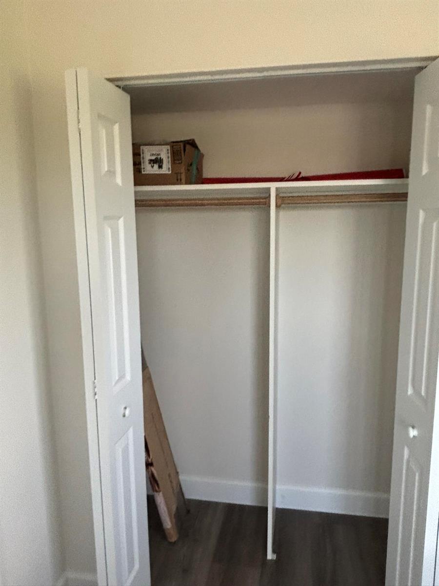 An open white closet with a shelf, hanging rod, and wood-look flooring — 2668 Garden Drive N # 312, FL 33461, FL