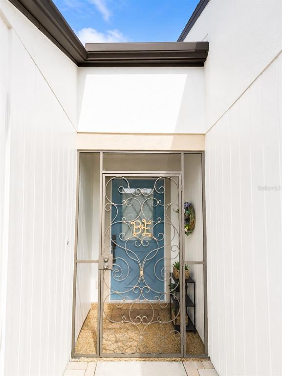 A blue front door with a decorative metal security gate sits in a recessed entryway — 1211 CAPRI ISLES BOULEVARD UNIT 122, VENICE, FL