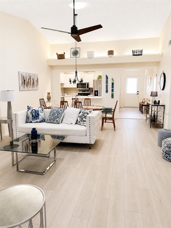 A living room with a white sofa, glass coffee table, and open kitchen in the background — 1211 CAPRI ISLES BOULEVARD UNIT 122, VENICE, FL