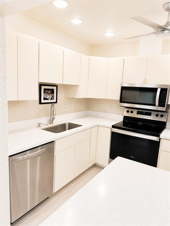 A kitchen features white cabinets, stainless steel appliances, and light-colored countertops — 1211 CAPRI ISLES BOULEVARD UNIT 122, VENICE, FL