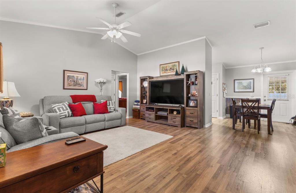 A living room with wood-look flooring, a gray sofa, and an open-concept dining area — 8599 N MESSINA LOOP, CRYSTAL RIVER, FL