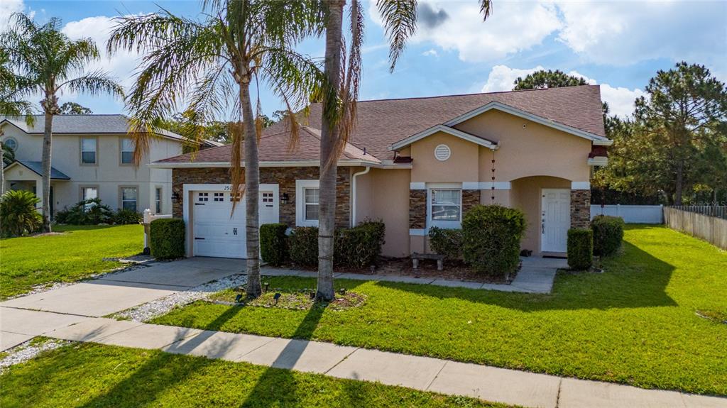 A single-story house with a stone facade, a one-car garage, and palm trees in front — 2902 PADDINGTON WAY, KISSIMMEE, FL