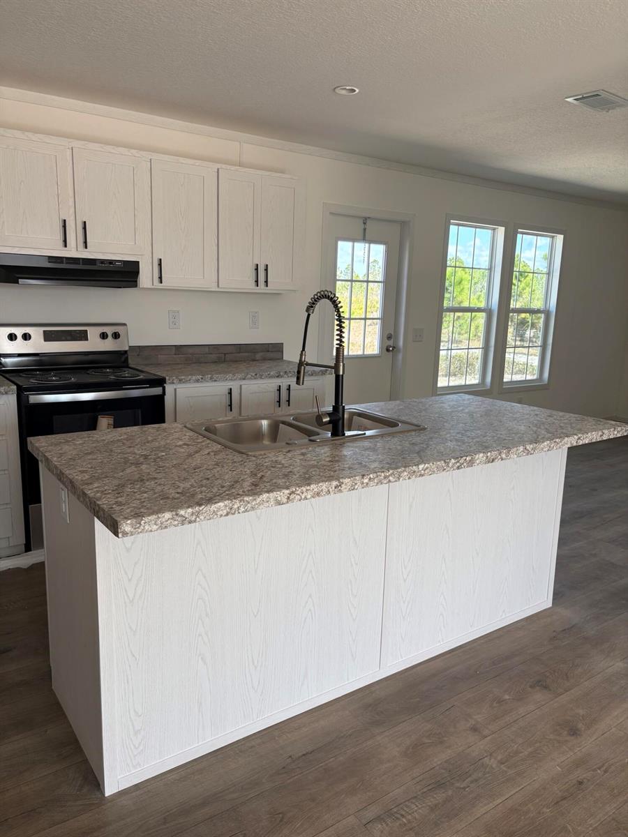 A kitchen features white wood-grain cabinets, a central island with a sink, and laminate countertops — 15983 NW 272nd Street, Okeechobee FL 34972, OKEECHOBEE, FL