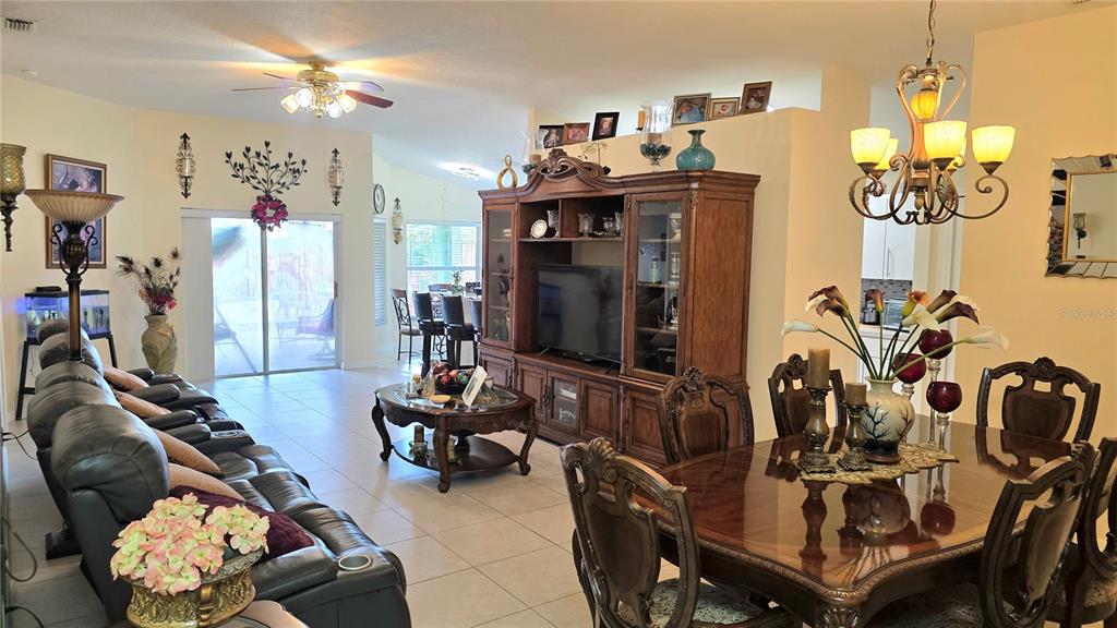 A living and dining room area features tile flooring, a wooden entertainment center, and chandeliers — 9708 WHITE BARN WAY, RIVERVIEW, FL