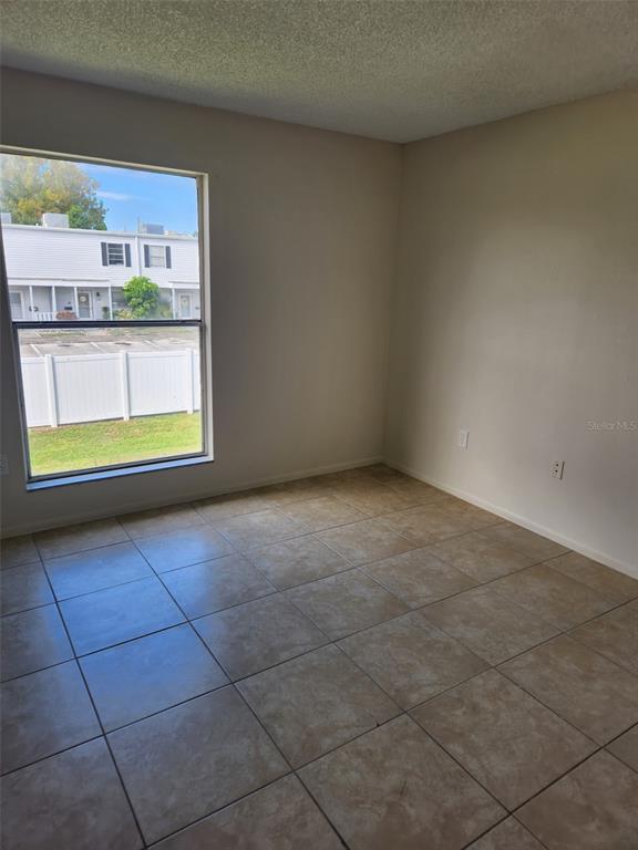 An empty room with beige tile flooring and a large window overlooking a white fence — 1882 CARALEE BOULEVARD UNIT 3, ORLANDO, FL