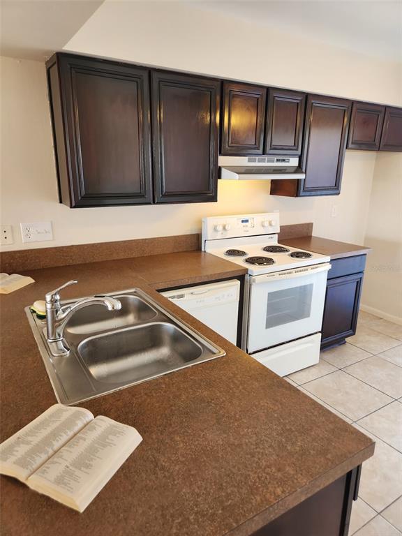 A kitchen features dark wood cabinets, brown countertops, a double sink, and white appliances — 1882 CARALEE BOULEVARD UNIT 3, ORLANDO, FL