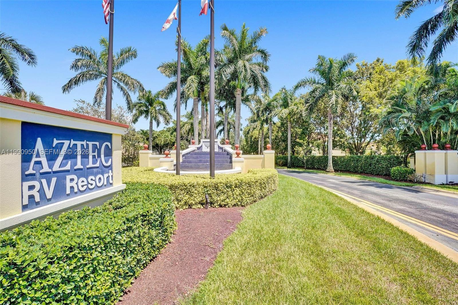 The entrance to the Aztec RV Resort features a blue sign, landscaping, and palm trees — 224 N Cortez Dr, Margate FL 33068, MARGATE, FL