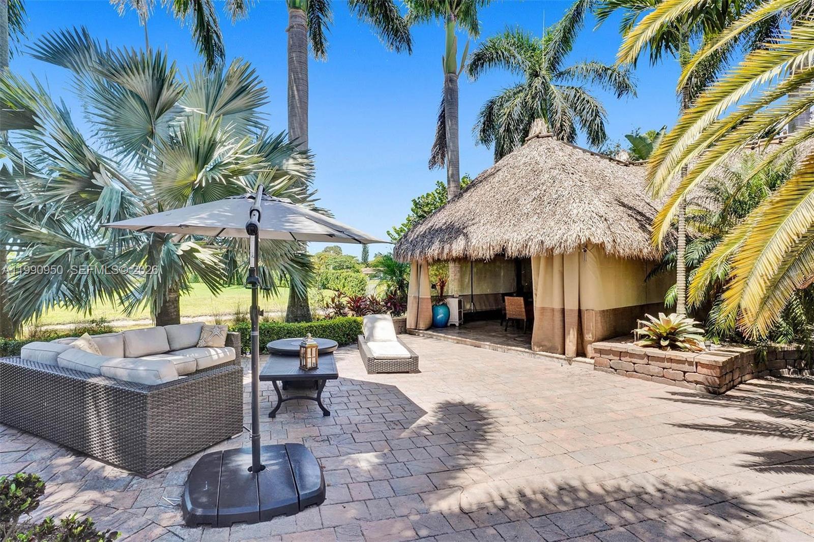 A patio features a wicker sofa, a thatched-roof gazebo, and a large umbrella — 224 N Cortez Dr, Margate FL 33068, MARGATE, FL