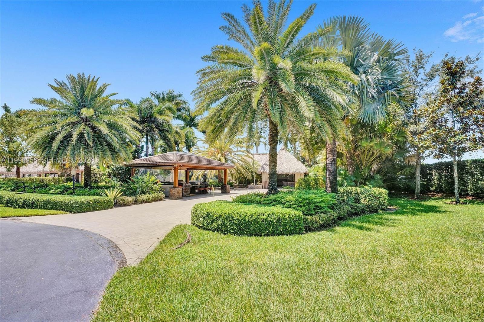 A paved driveway leads to a covered outdoor kitchen and a thatched-roof gazebo — 224 N Cortez Dr, Margate FL 33068, MARGATE, FL