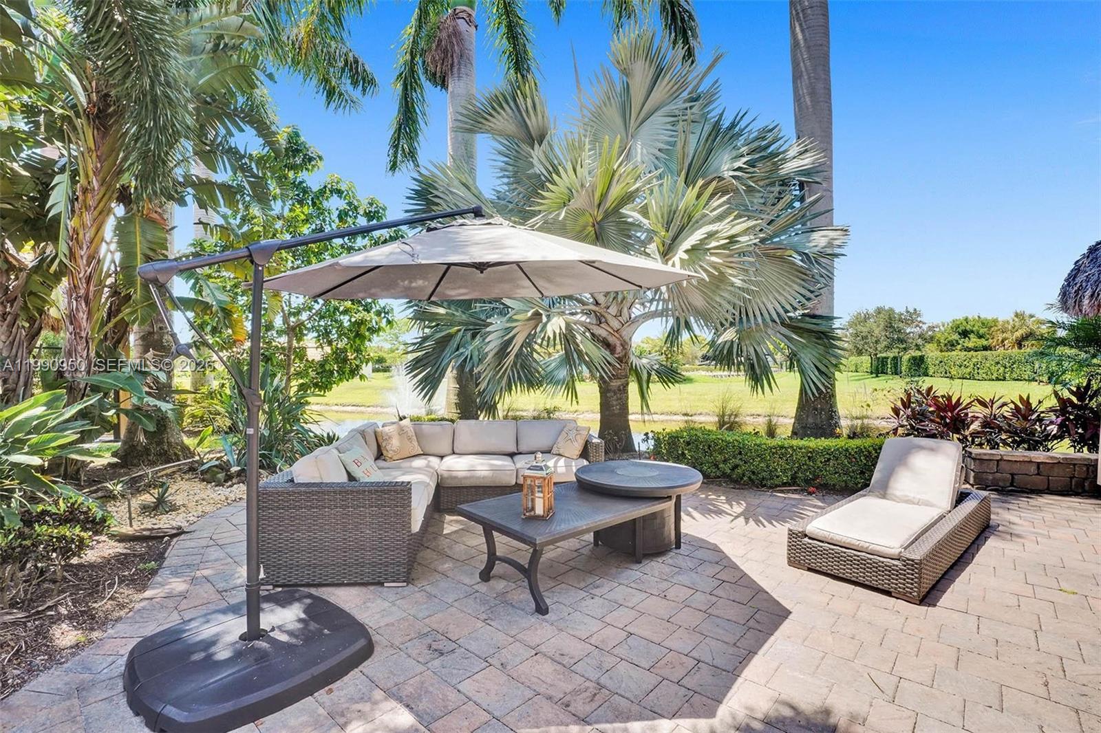 A patio features a wicker sectional sofa, a lounge chair, and an umbrella on pavers — 224 N Cortez Dr, Margate FL 33068, MARGATE, FL