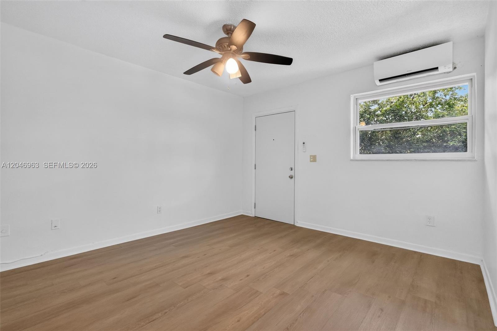 An empty room features light wood-look flooring, a ceiling fan, and a wall-mounted air conditioner — 458 SW 9th St # 1, Miami FL 33130, MIAMI, FL