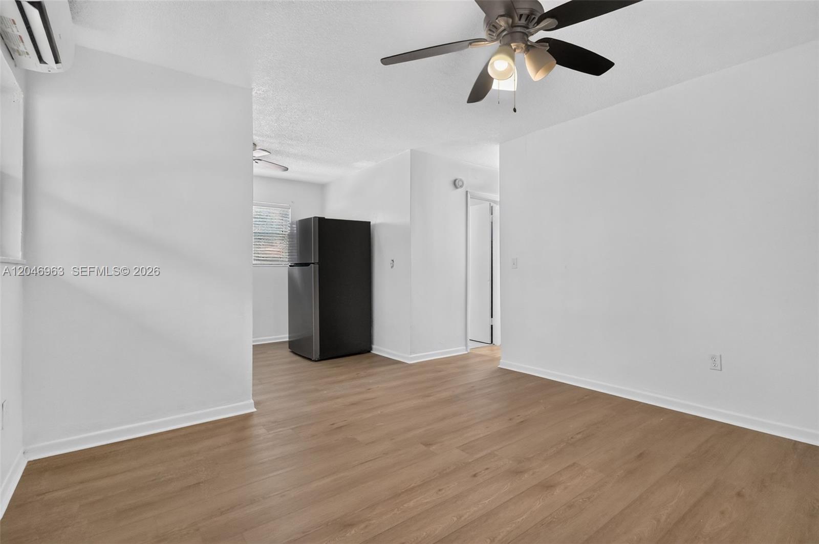 A room with light wood-look flooring, white walls, a ceiling fan, and a black refrigerator — 458 SW 9th St # 1, Miami FL 33130, MIAMI, FL