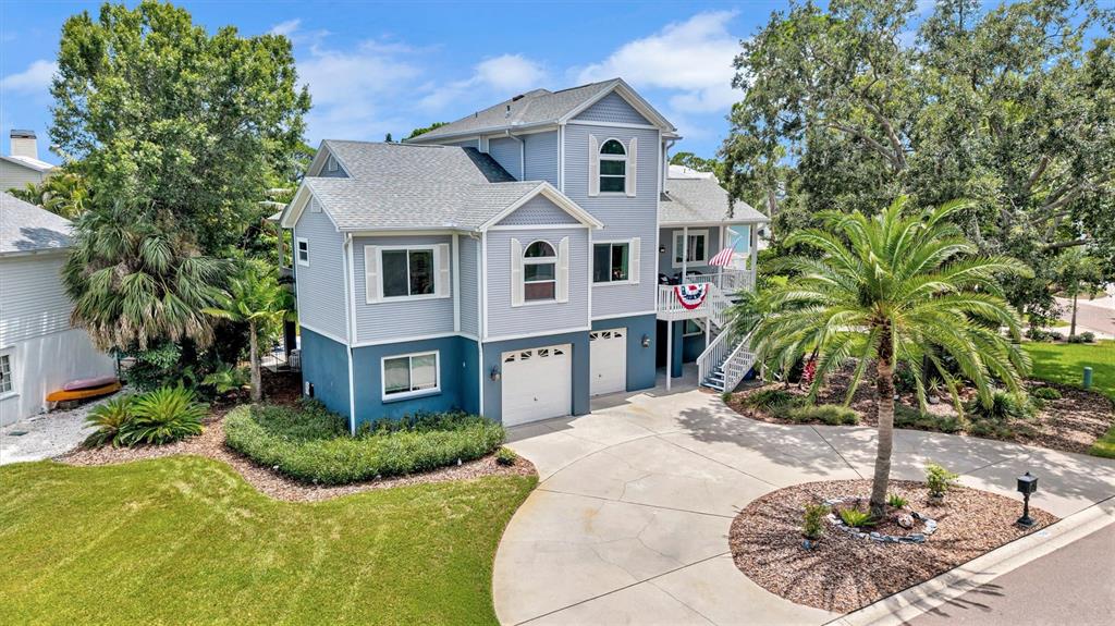 A multi-story house with blue siding, a concrete driveway, and a palm tree in front — 760 SOUNDVIEW DRIVE, PALM HARBOR, FL