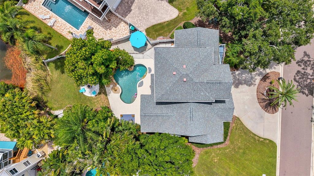 An aerial view shows a house with a grey roof, a pool, and surrounding landscaping — 760 SOUNDVIEW DRIVE, PALM HARBOR, FL