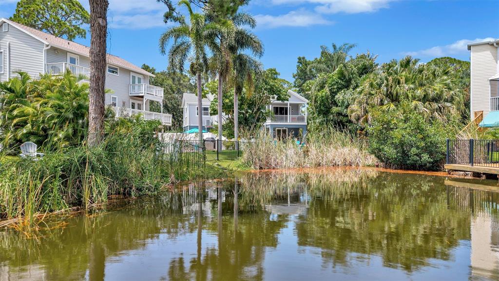 A pond sits in front of multi-story residential buildings surrounded by palm trees and vegetation — 760 SOUNDVIEW DRIVE, PALM HARBOR, FL