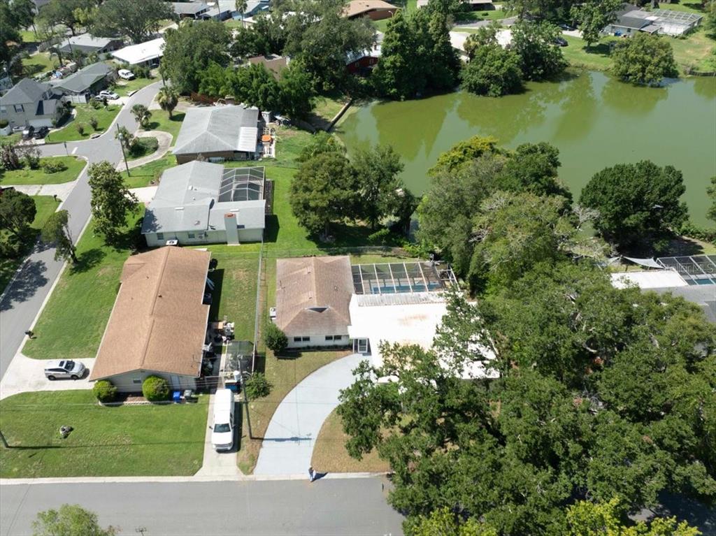 An aerial view shows a suburban neighborhood with houses, a pool, and a small lake — 1925 JOHN ARTHUR WAY, LAKELAND, FL