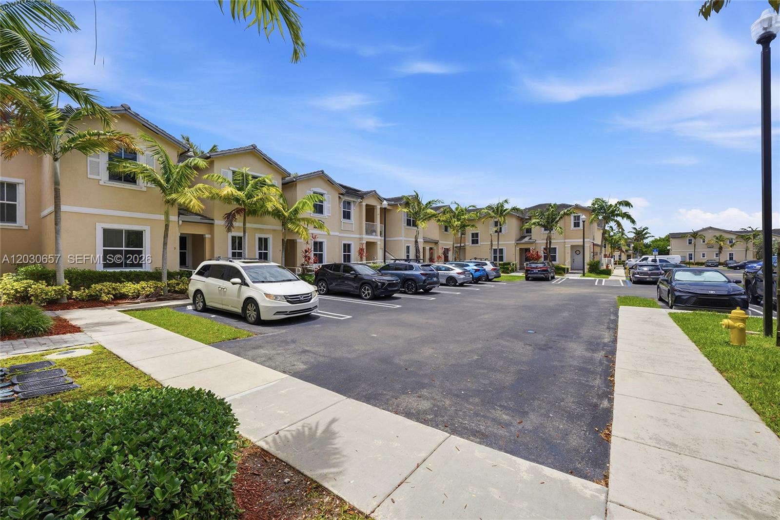 A parking lot sits in front of a row of multi-story residential buildings with palm trees — 142 SE 28th Ter # 6, Homestead FL 33033, HOMESTEAD, FL