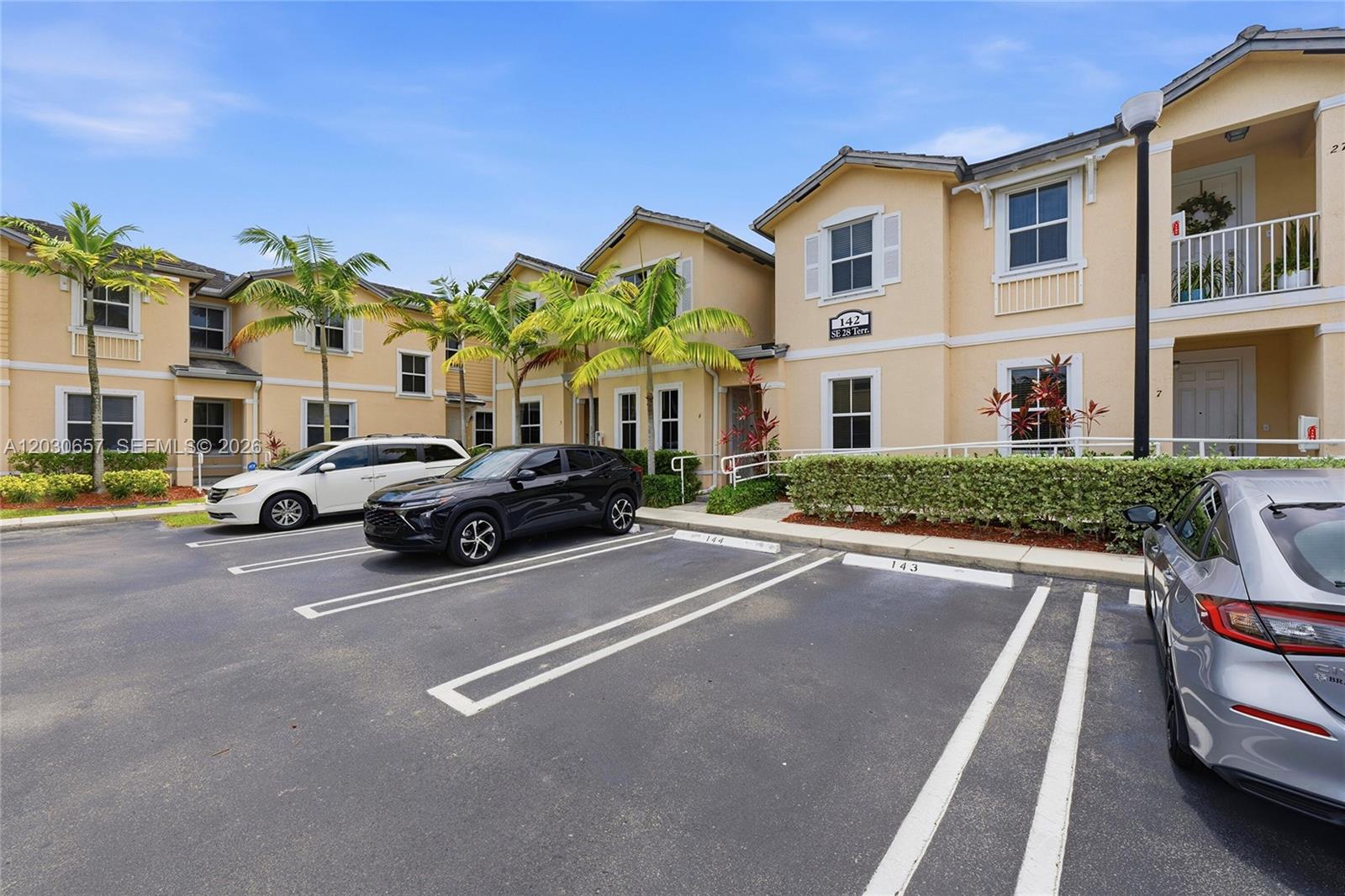 A parking lot sits in front of a row of two-story tan residential buildings — 142 SE 28th Ter # 6, Homestead FL 33033, HOMESTEAD, FL