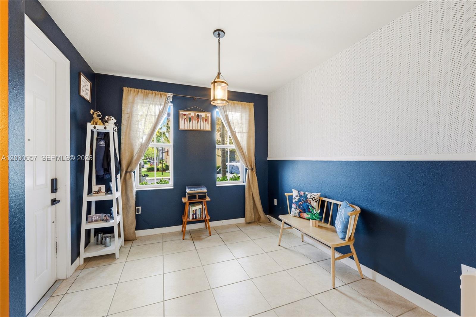 A room with blue walls, a patterned accent wall, tile floors, and a wooden bench — 142 SE 28th Ter # 6, Homestead FL 33033, HOMESTEAD, FL