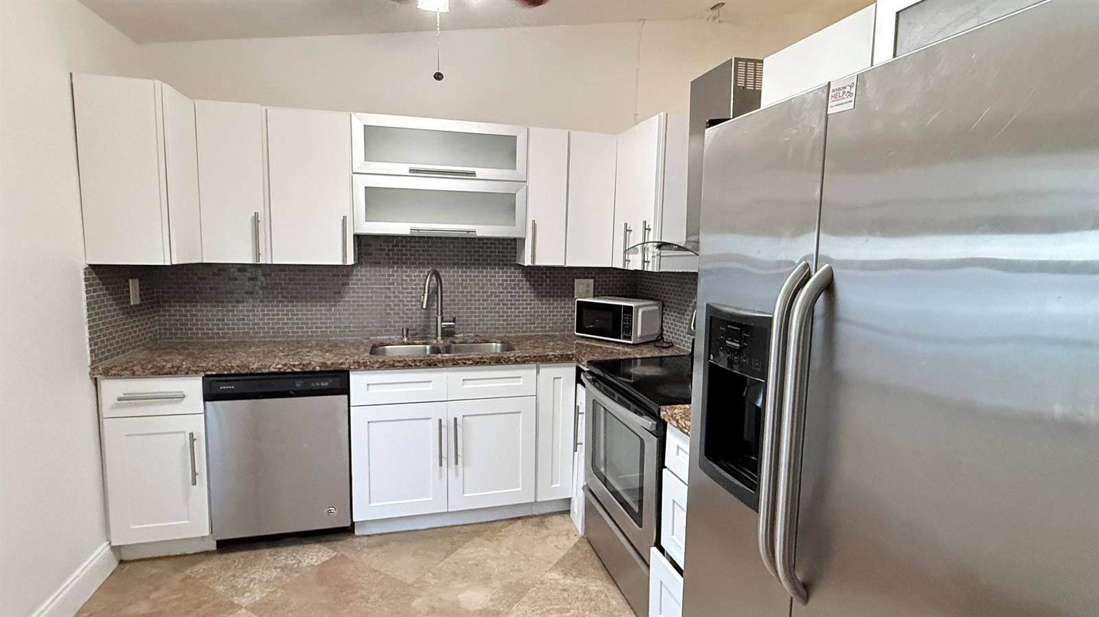 A kitchen features white cabinets, stainless steel appliances, a brown countertop, and a tiled backsplash — 4313 NW 6th Avenue, Pompano Beach FL 33064, POMPANO BEACH, FL