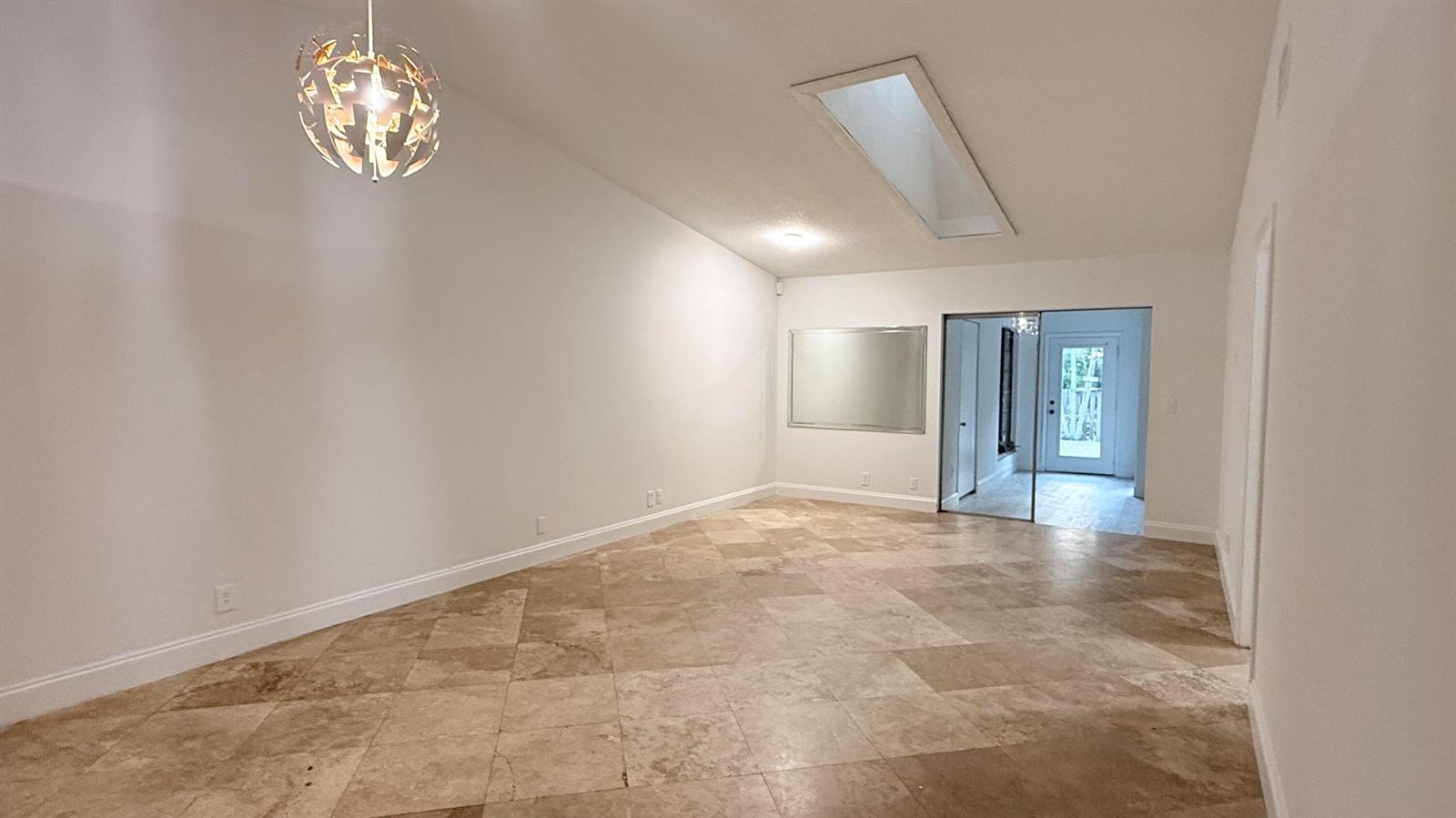 A spacious room features light-colored tile flooring, a vaulted ceiling with a skylight, and lighting — 4313 NW 6th Avenue, Pompano Beach FL 33064, POMPANO BEACH, FL