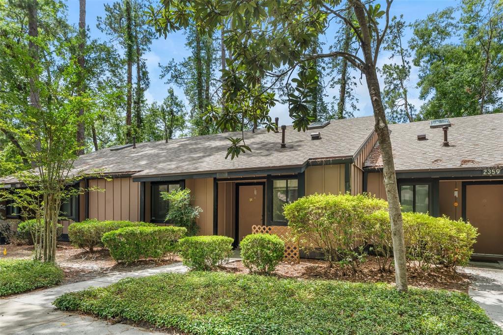 A single-story tan building with dark trim is surrounded by trees and green landscaping — 2355 NW 45TH LANE, GAINESVILLE, FL