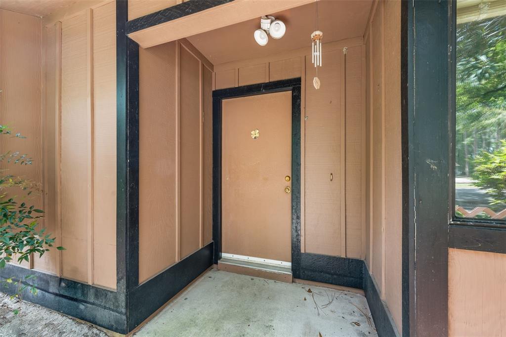A tan front door with black trim is set within a covered concrete entryway — 2355 NW 45TH LANE, GAINESVILLE, FL