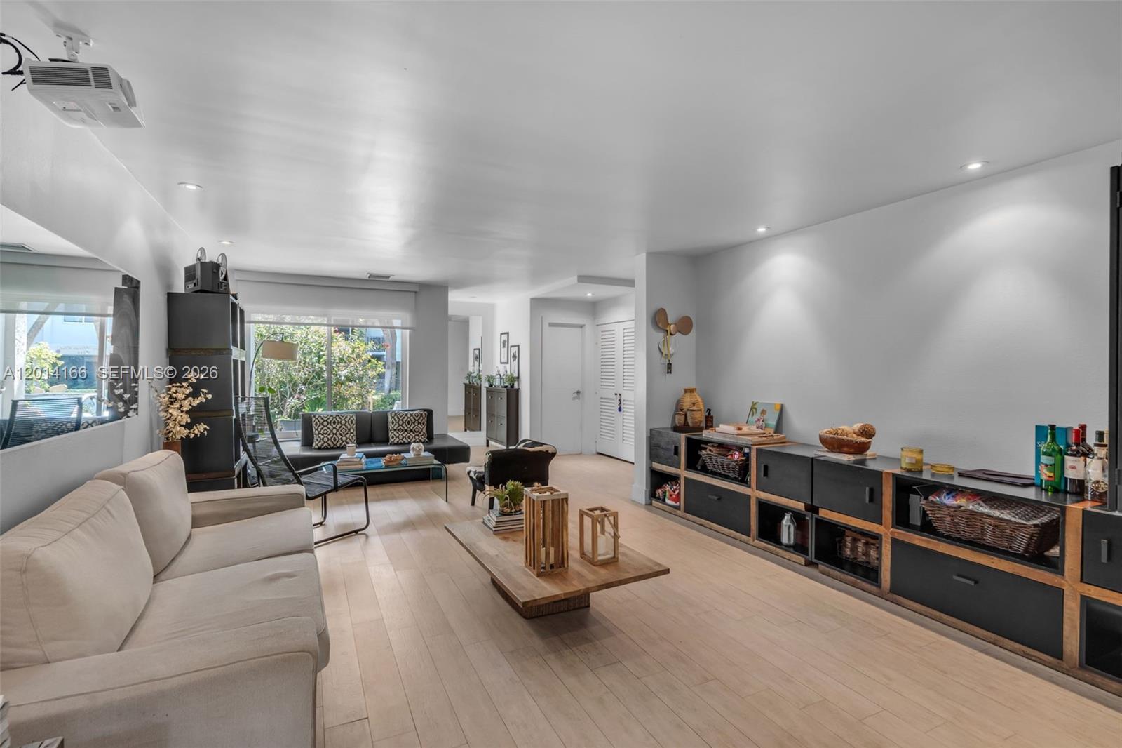 A living room features light wood flooring, a beige sofa, and a long media console — 232 Sea View Dr # 108, Key Biscayne FL 33149, KEY BISCAYNE, FL