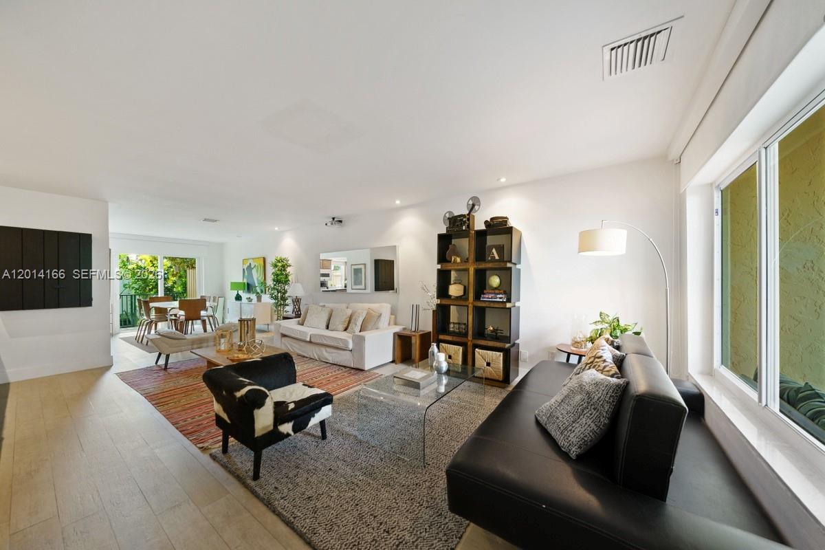 A spacious living room features light wood floors, a black leather sofa, and a bookshelf — 232 Sea View Dr # 108, Key Biscayne FL 33149, KEY BISCAYNE, FL