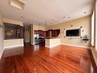 An open-concept living area features hardwood floors, a kitchen with dark cabinets, and a television — 44 S MAGNOLIA AVENUE, OCALA, FL