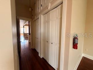 A hallway with hardwood floors features white paneled closet doors and a wall-mounted fire extinguisher — 44 S MAGNOLIA AVENUE, OCALA, FL