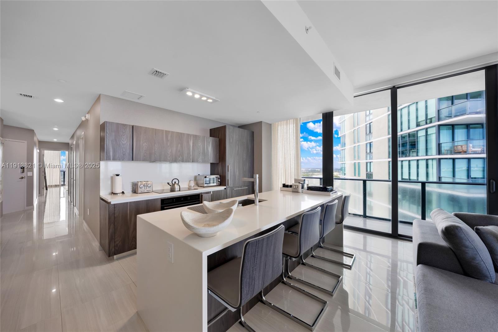 A modern kitchen features a white island with bar seating and dark wood cabinetry — 480 NE 31st St # 2807, Miami FL 33137, MIAMI, FL