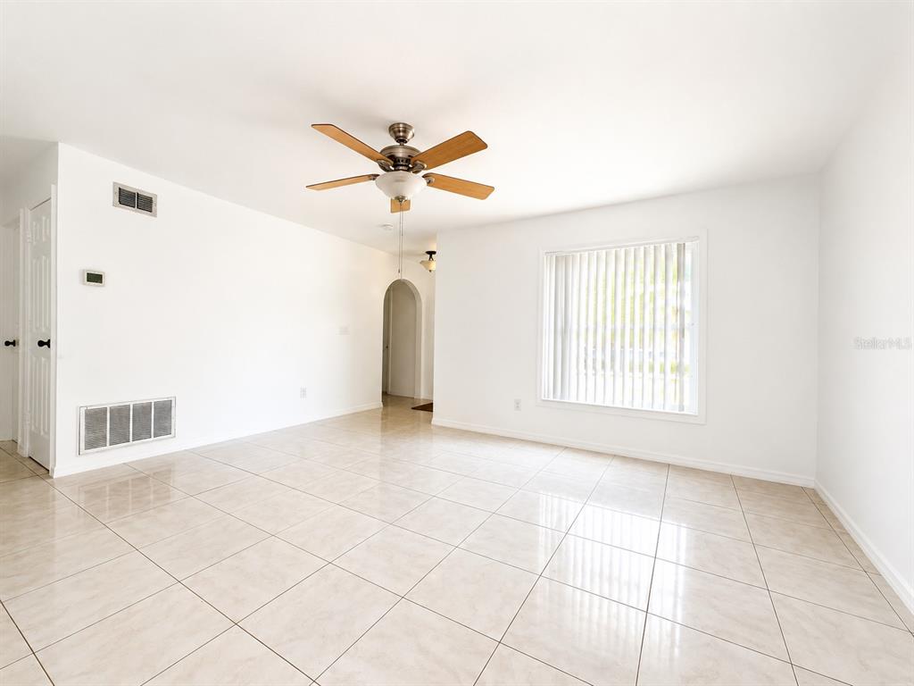 A bright, empty room features white walls, light-colored tiled flooring, and a ceiling fan — 714 WEST COURT, LONGWOOD, FL