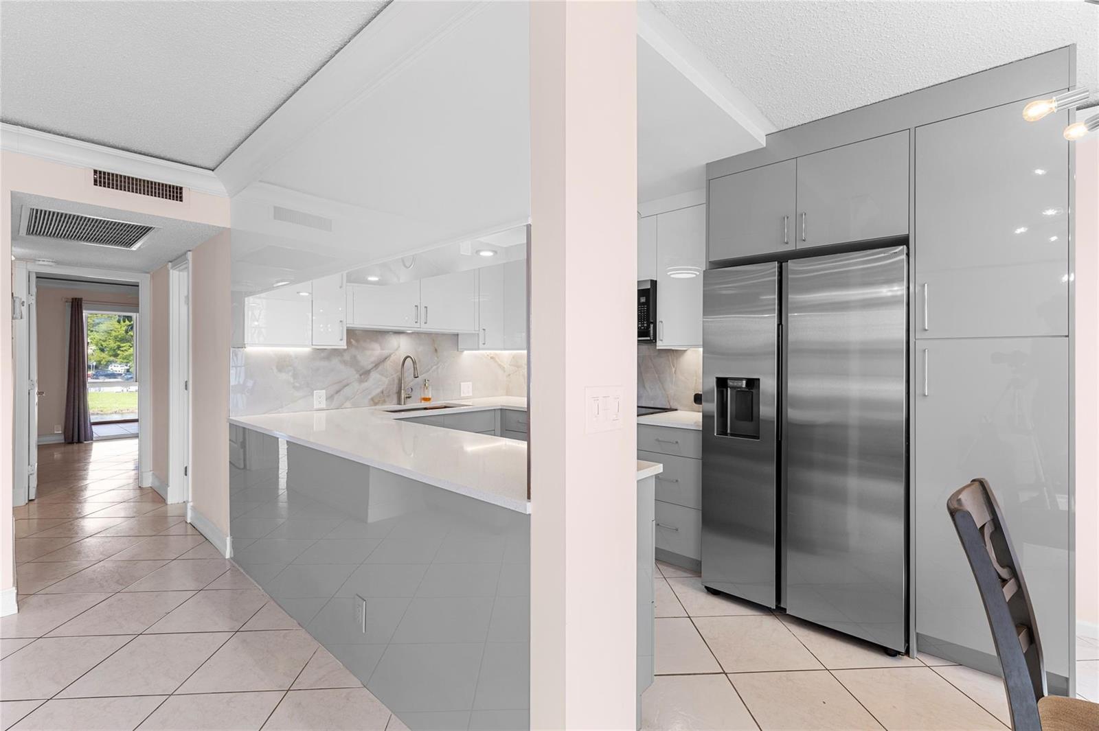 An open-concept living and dining area features white cabinetry, tile flooring, and stained-glass windows — 2122 Cambridge F # 2122, Deerfield Beach FL 33442, DEERFIELD BEACH, FL